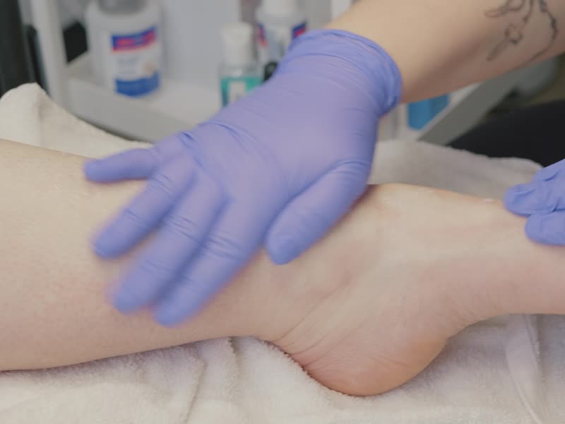 Gloved hands gently massaging a foot